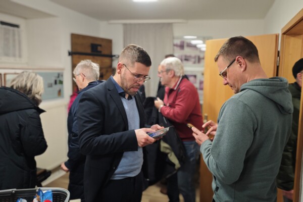 Bürgermeister Sven Schrade tauscht Kontaktdaten am Handy mit einem Bürger.