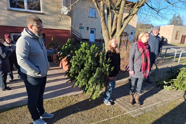 Ein Vater und seine Tochter halten einen Tannenbaum in die Höhe.